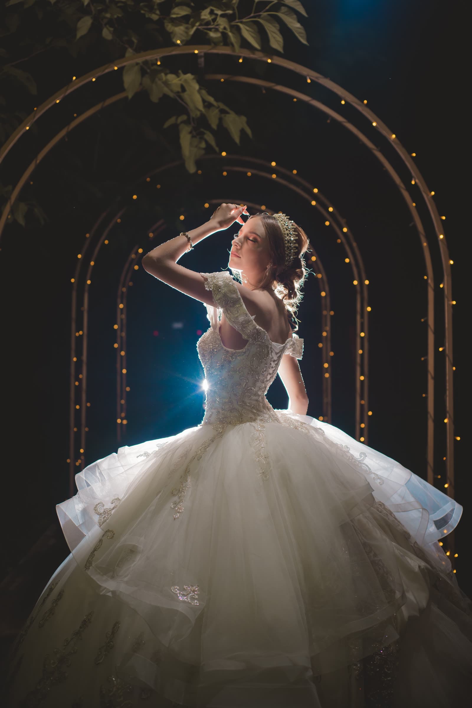 Quinceañera bajo arcos de luz al anochecer
