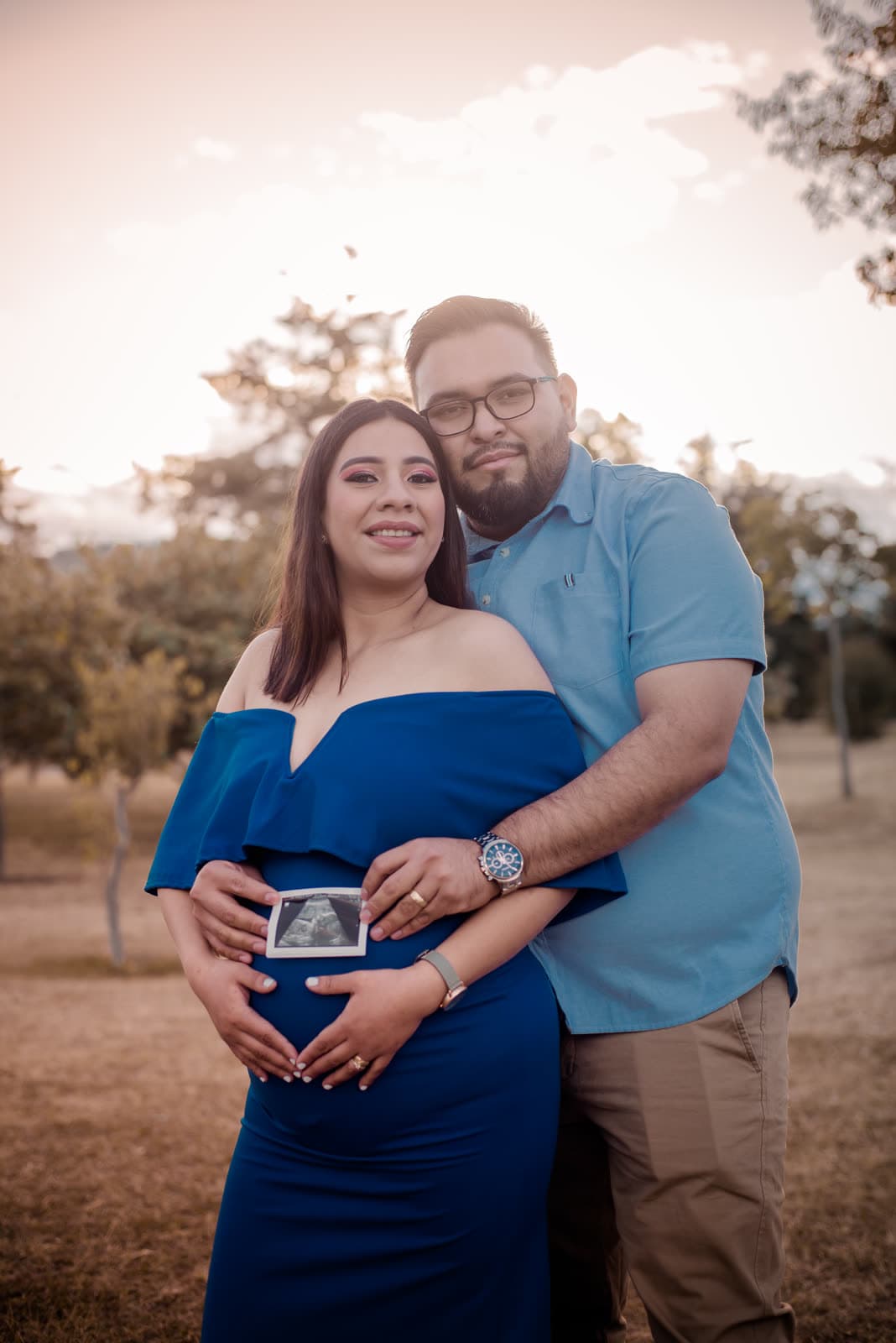 Pareja esperando bebé bajo los árboles