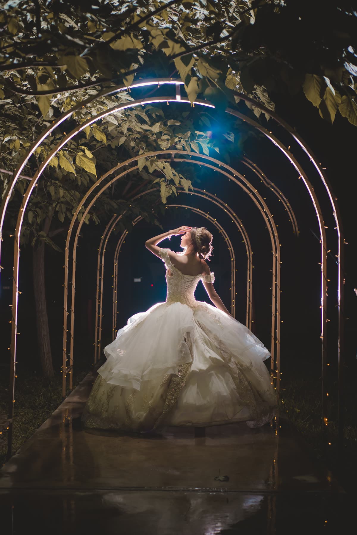 Quinceañera bajo un túnel de arcos iluminados